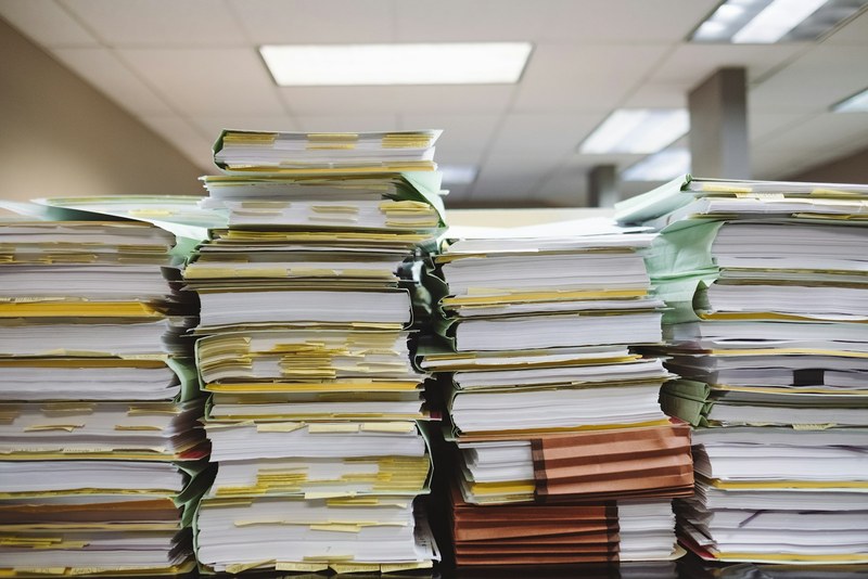Stacks of paper files and folders on an office desk